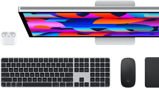 Top down view of Studio Display monitor, black Magic Keyboard, black Magic Mouse, black Magic Trackpad, and white AirPods case